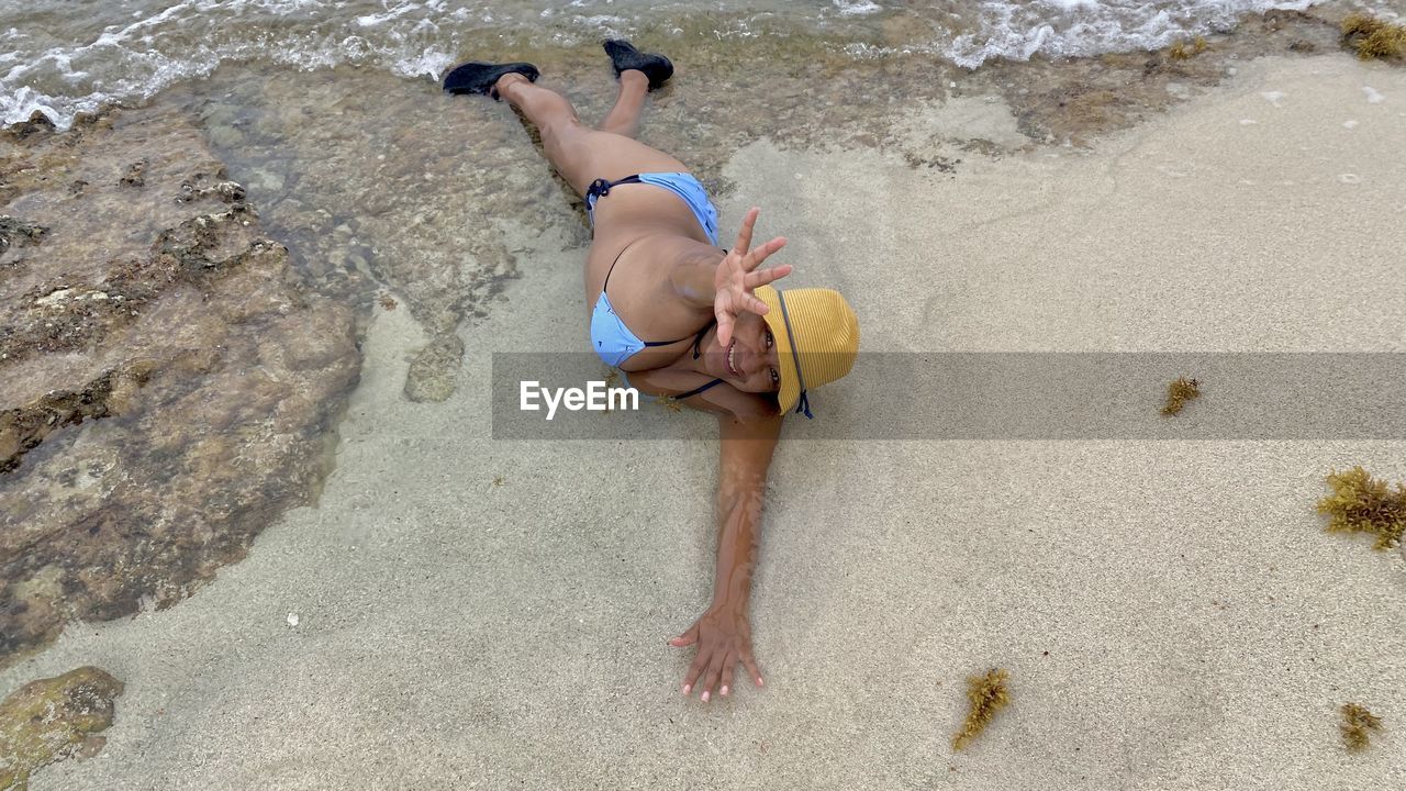 HIGH ANGLE VIEW OF SHIRTLESS MAN LYING ON BEACH