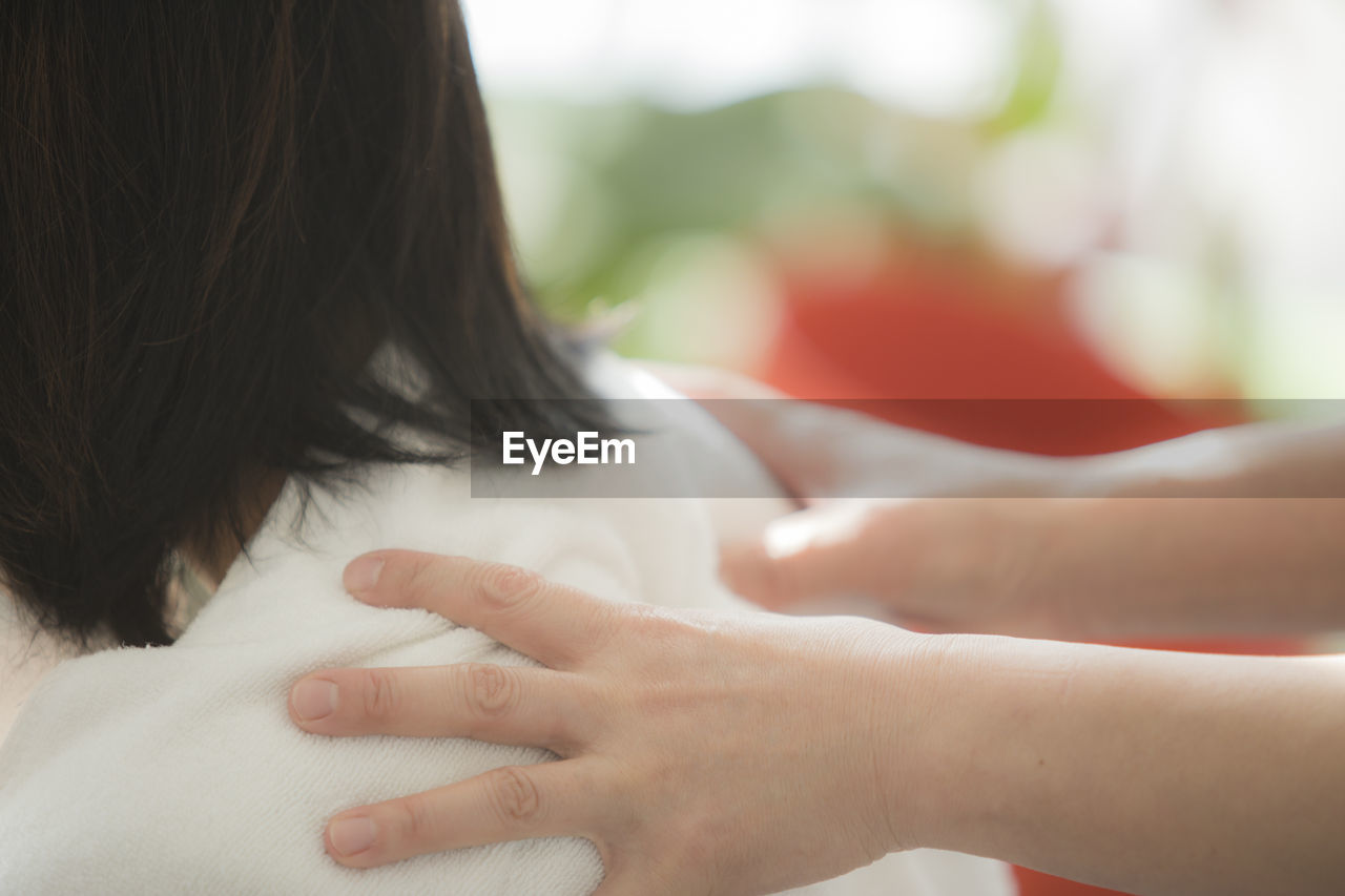 Cropped hands giving back massage to woman at spa