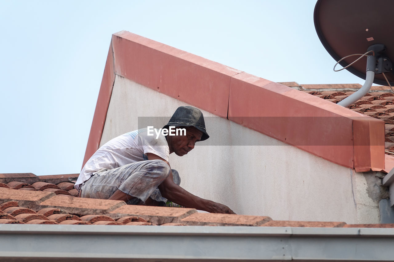 SIDE VIEW OF MAN WORKING ON WALL