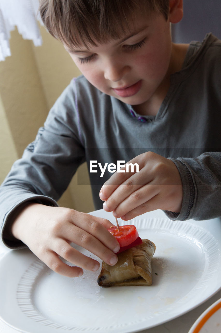 Boy preparing beef kebab in kitchen