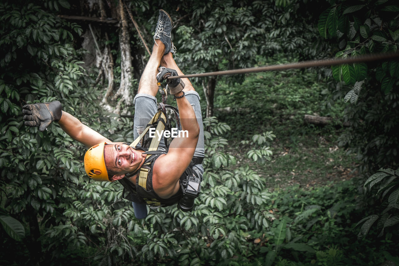 Young strong man zip line in jungle