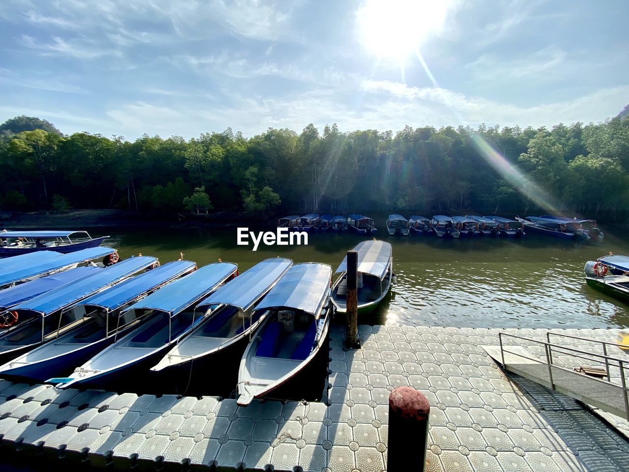 Boats moored on lake against sky on sunny day