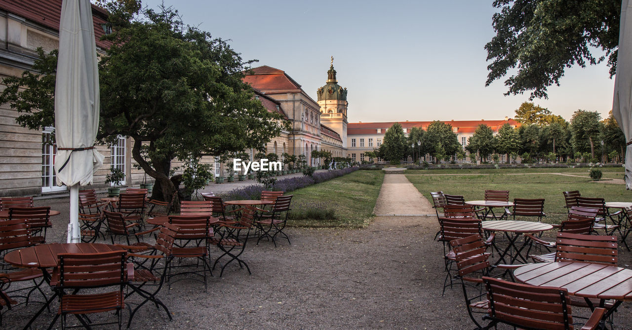 EMPTY CHAIRS AND TABLES AGAINST SKY IN CITY