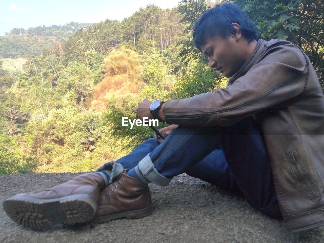 Side view of young man sitting outdoors