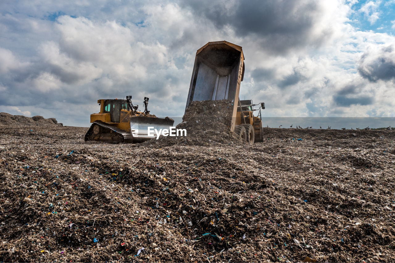 A dumper truck on a large waste management landfill site dumping rubbish in an environmental issue