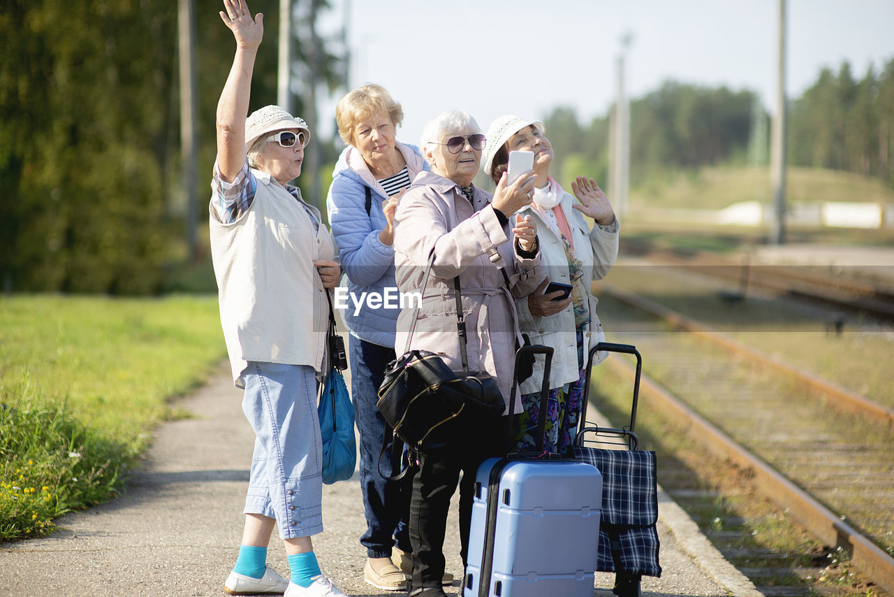 Group of  senior women take a self-portrait on platform waiting  train to travel during a  pandemic