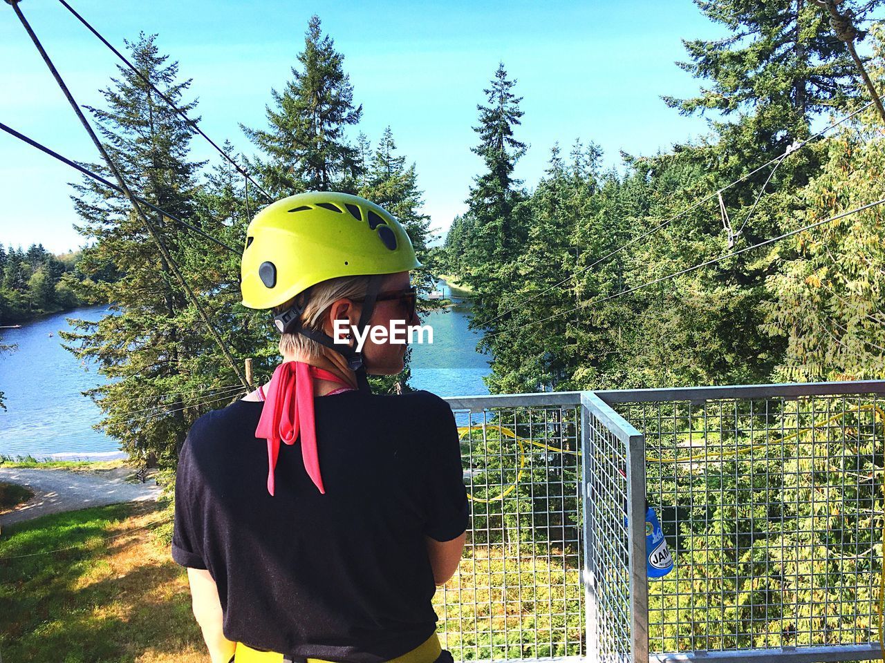 Young woman wearing helmet while zip lining by tree