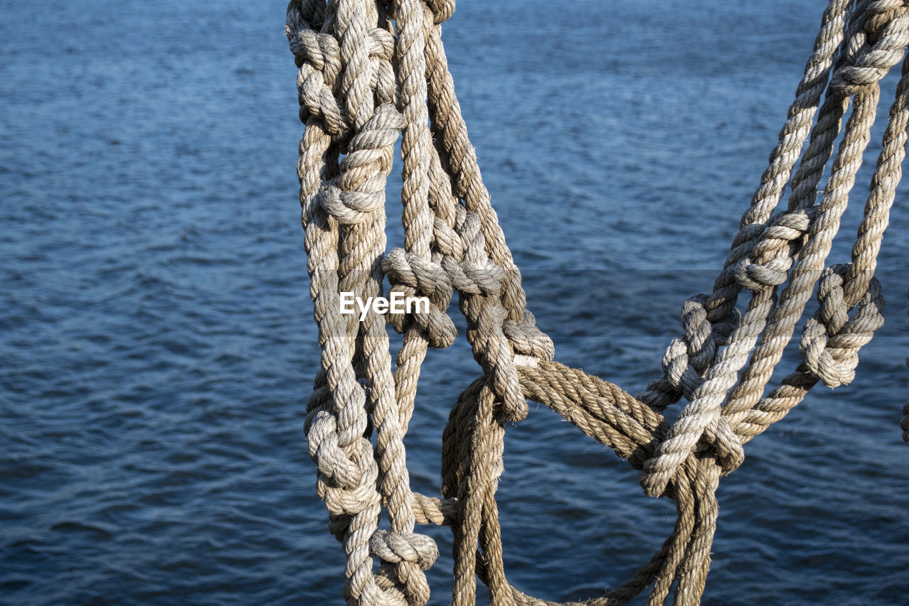 Close-up of rope hanging against sea