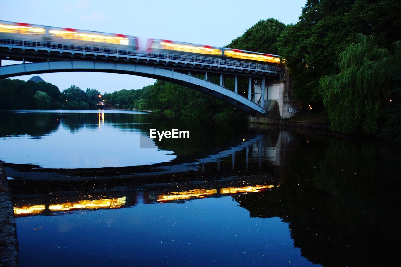 Arch bridge over river against sky at night