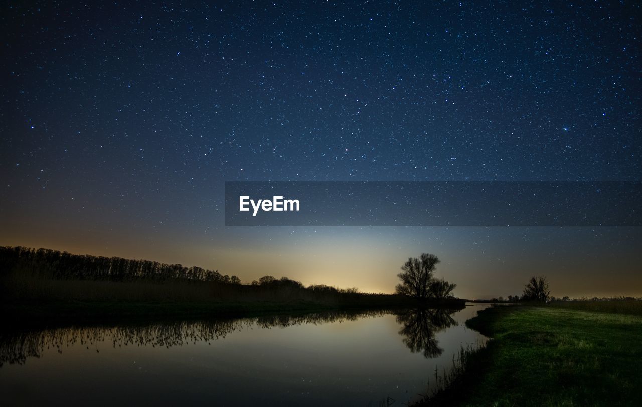 Scenic view of lake against sky at night