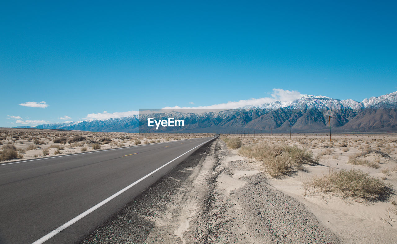 Road by mountains against clear blue sky