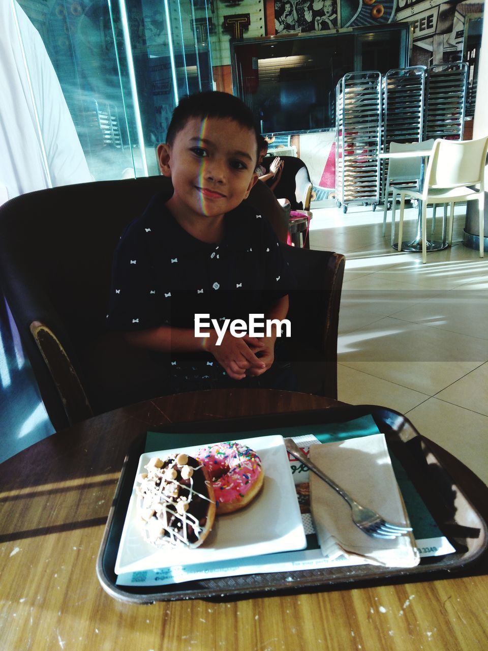 Portrait of boy eating donut at restaurant