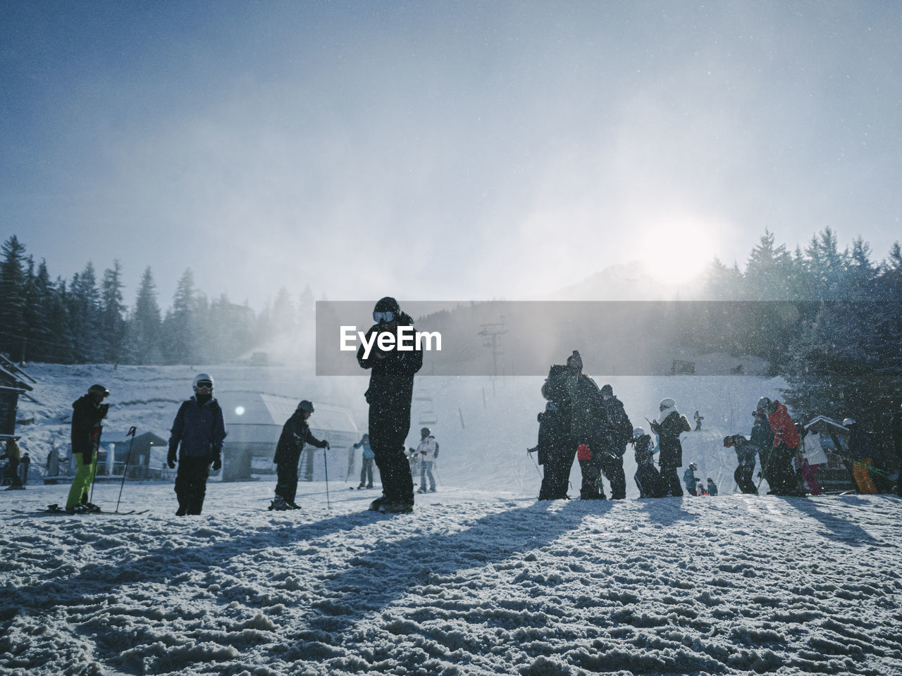 People on snow covered field against sky