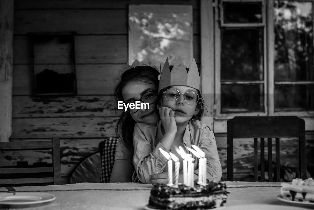 Portrait of sibling on table against the birthday cake