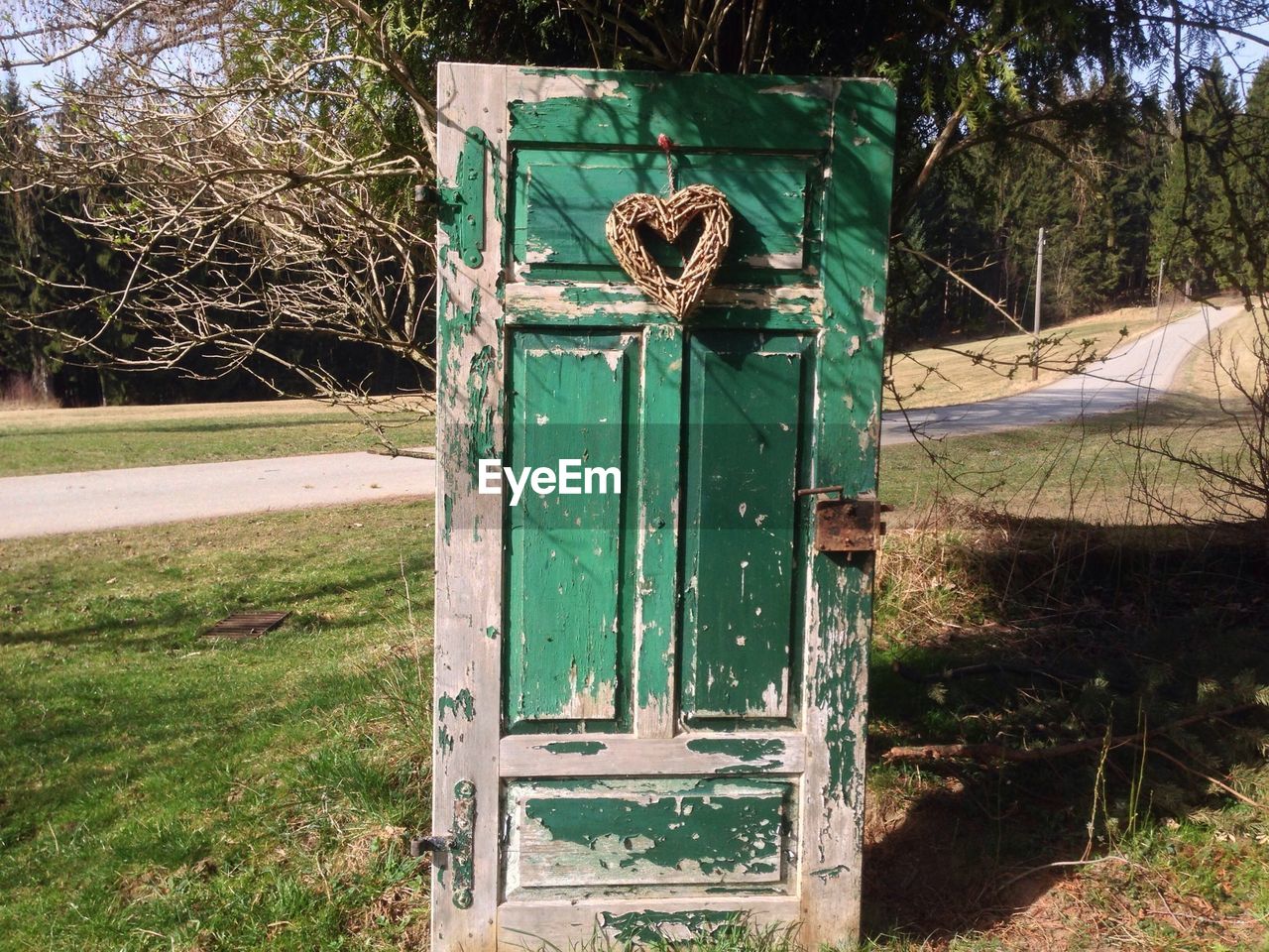 Abandoned door with heart on grassy field