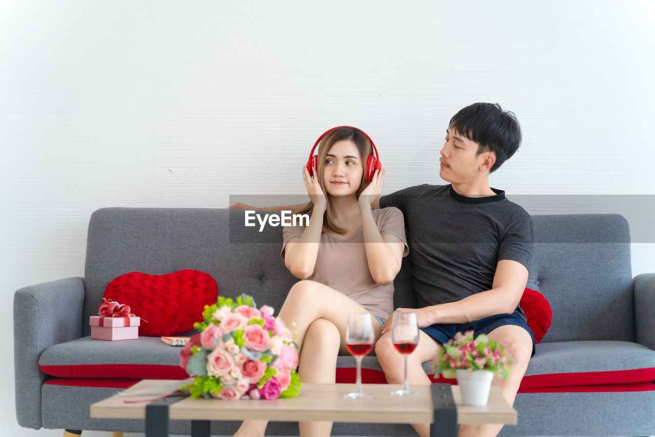 YOUNG COUPLE SITTING ON SOFA AT HOME