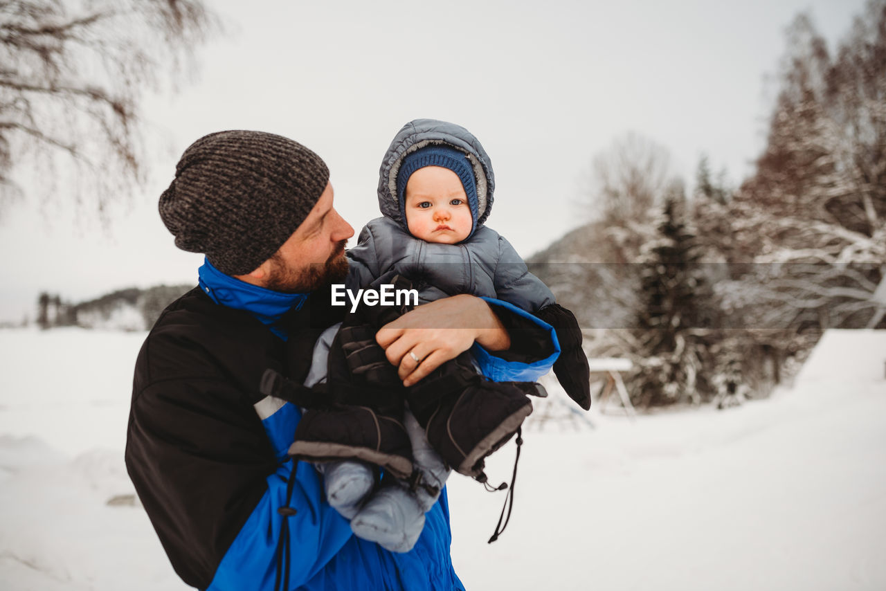 Dad and baby on cold cloudy day in the snow in mountain forest