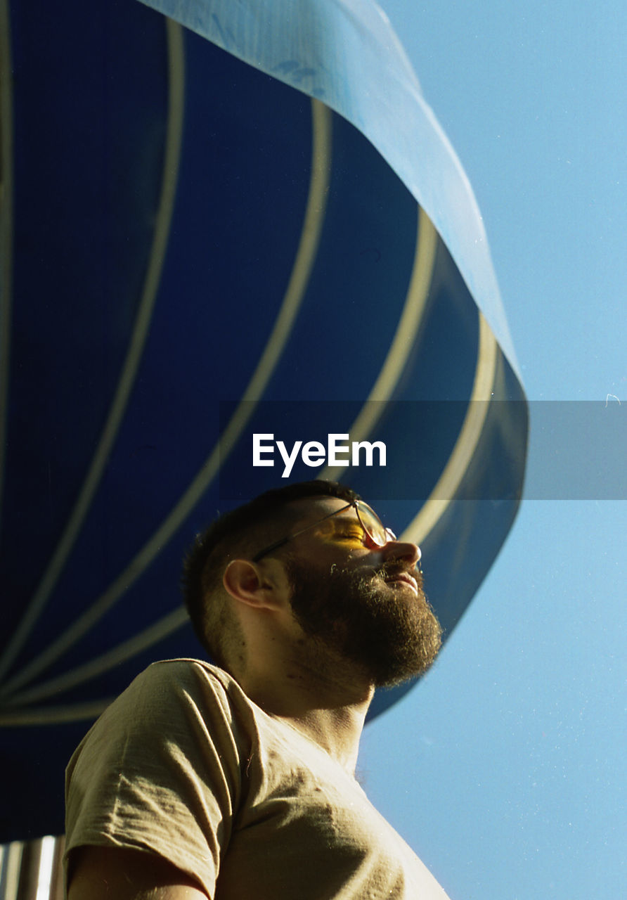 Portrait of young man looking away against blue sky