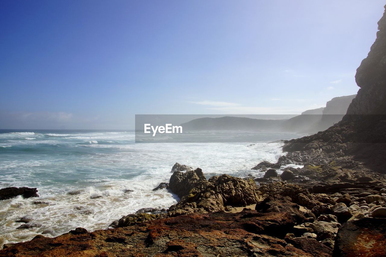 Waves reaching at shore against sky