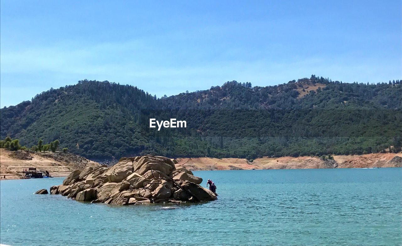 Scenic view of sea and mountains against clear blue sky