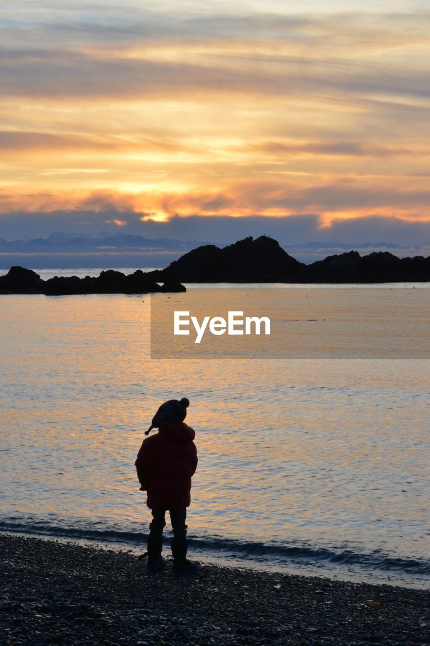 SILHOUETTE OF MAN ON BEACH AGAINST SKY