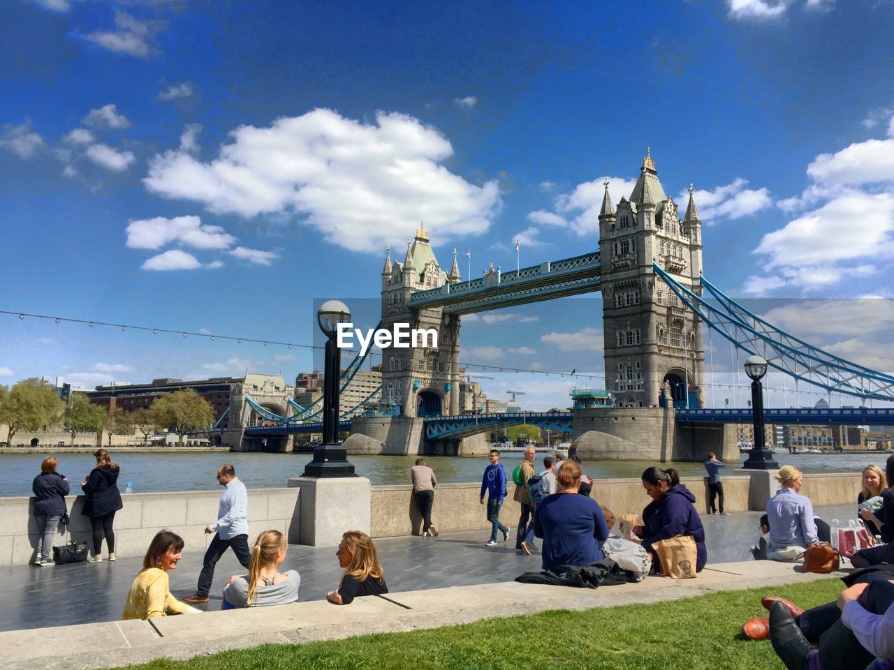 People on promenade by thames river against tower bridge