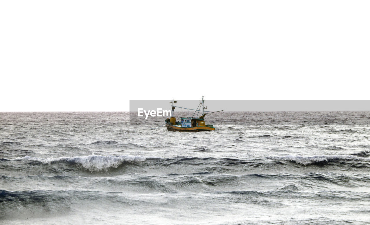 Boat sailing in sea against clear sky