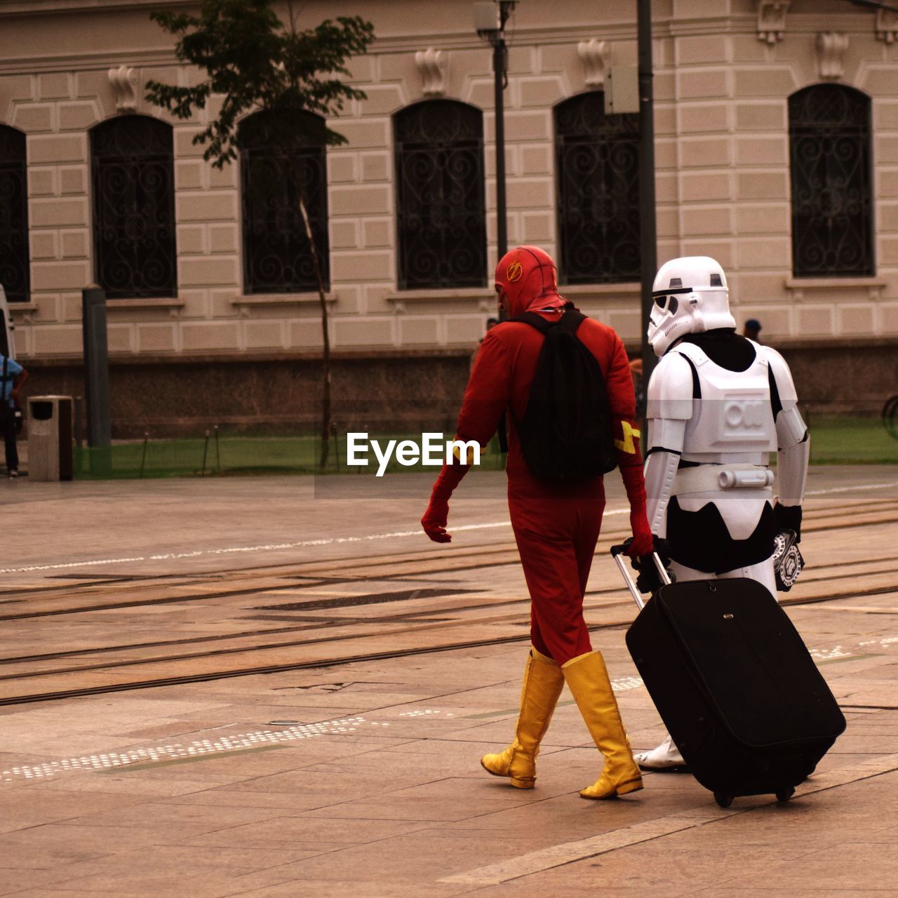 Rear view of people in costume walking on footpath