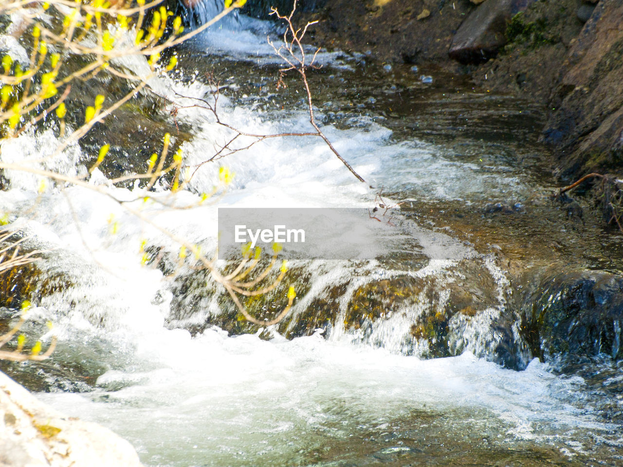 HIGH ANGLE VIEW OF WATERFALL ALONG RIVER