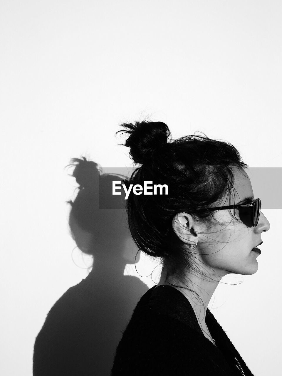 Profile view of woman wearing sunglasses against wall