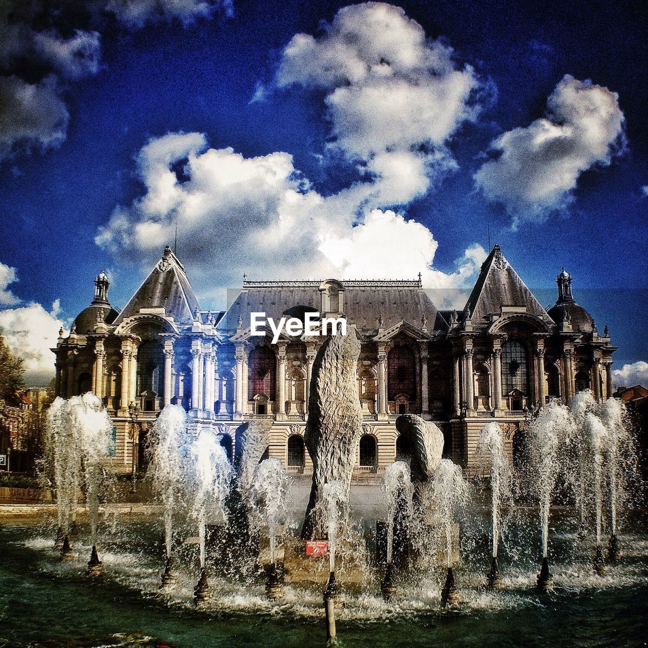 Exterior of museum with fountains against cloudy sky