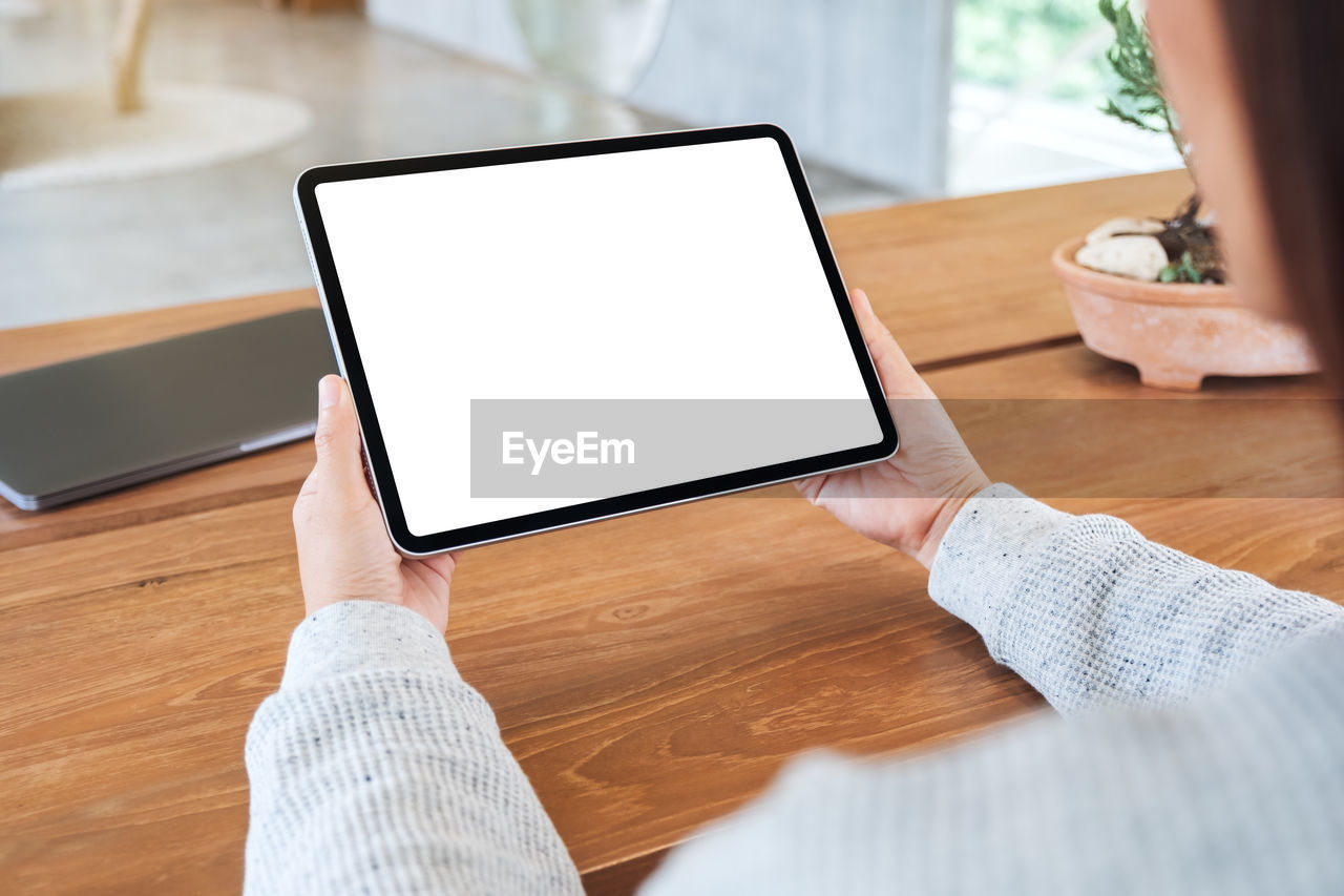 cropped hands using digital tablet at table