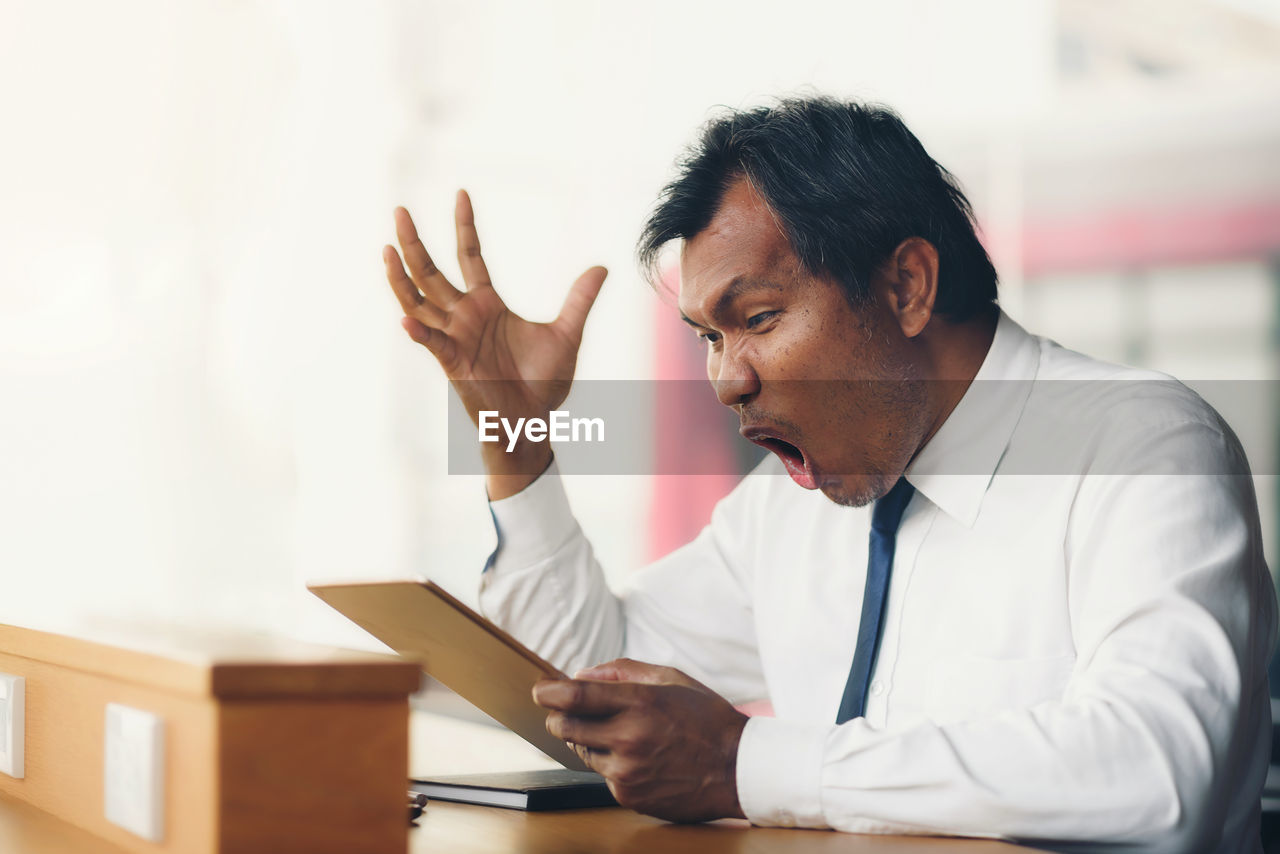 View of frustrated man sitting in office