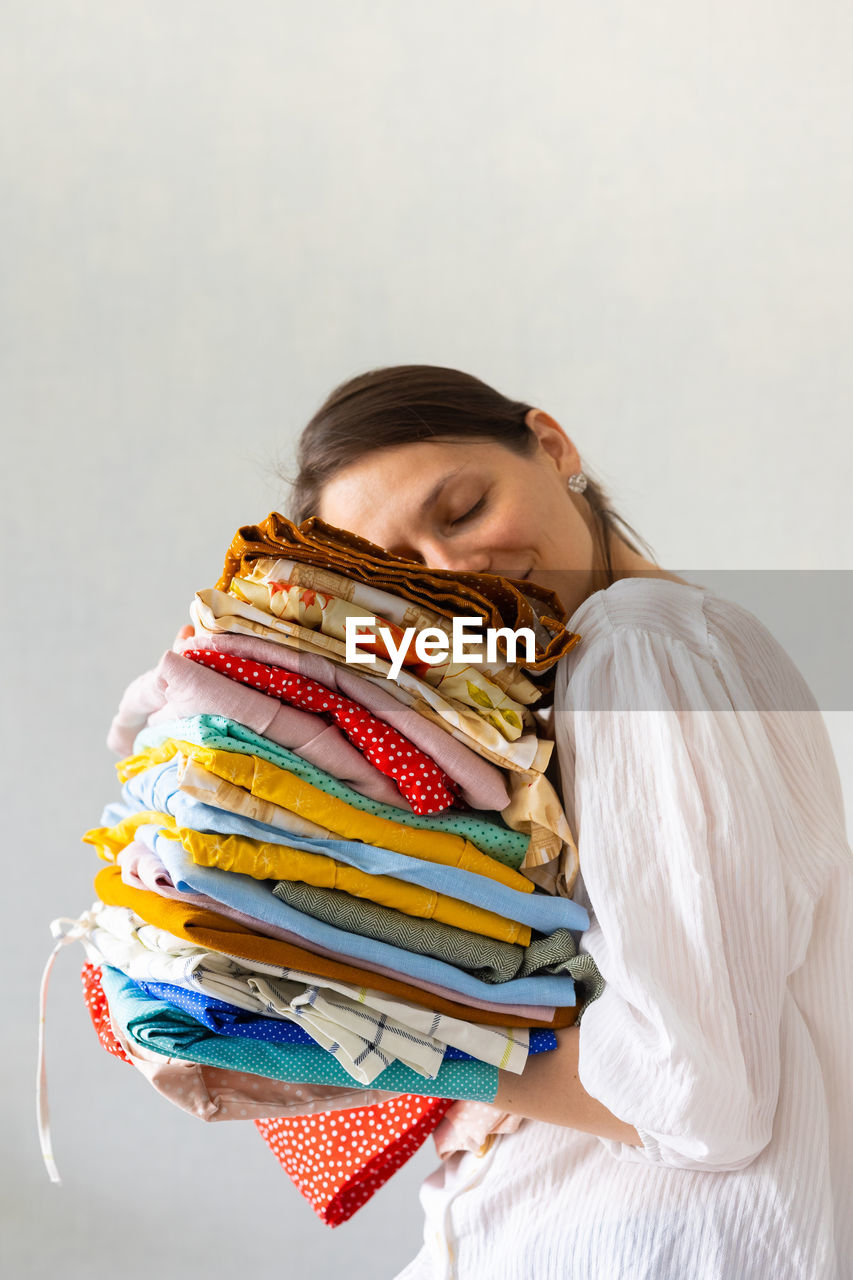 A european woman holds holding a stack of clothes in a wardrobe or boutique.  laundry or recycling