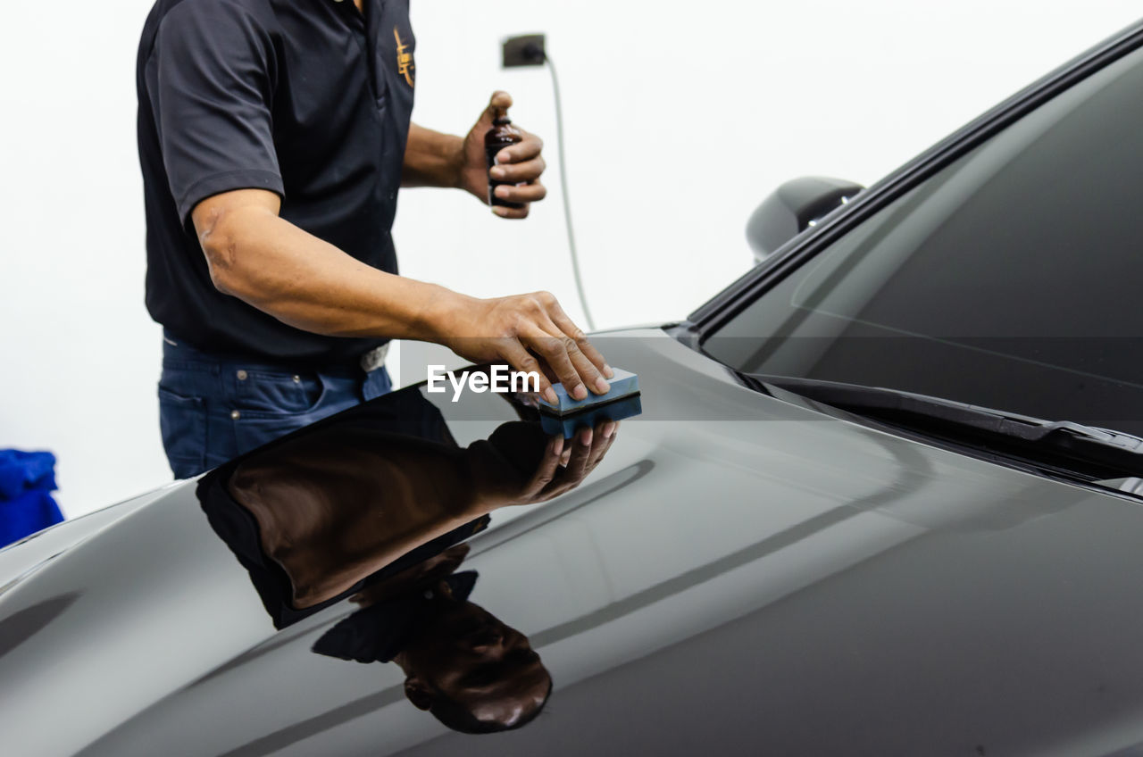 Midsection of man cleaning car