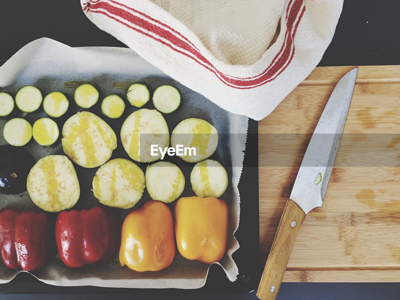 Directly above shot of vegetables in tray by knife on wooden cutting board