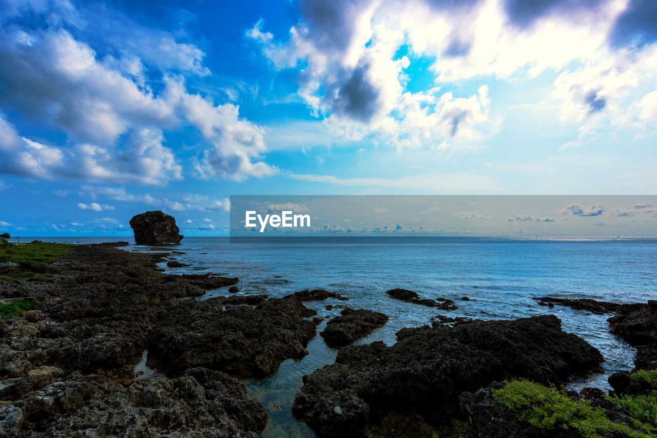 Scenic view of rocky shore and sea against sky