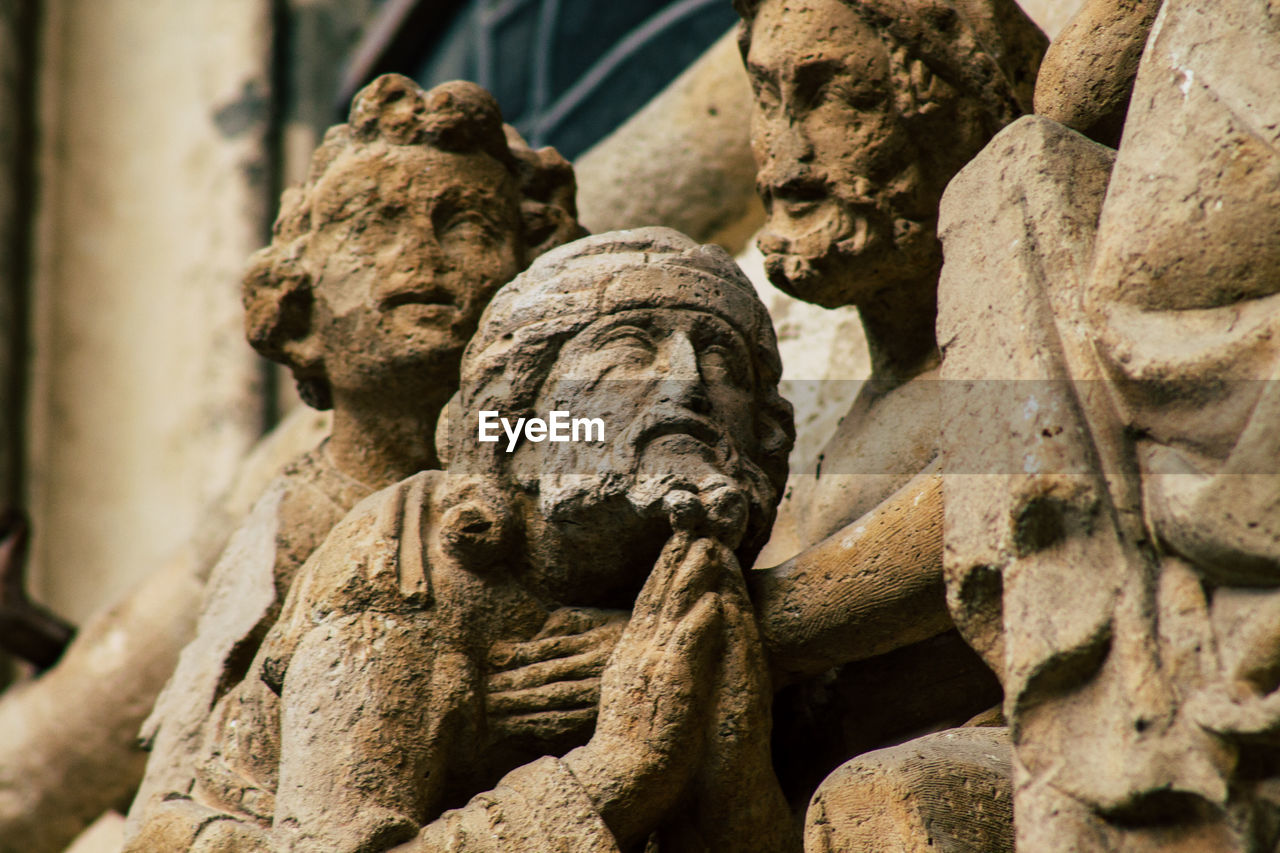 LOW ANGLE VIEW OF STATUE AGAINST OLD WALL