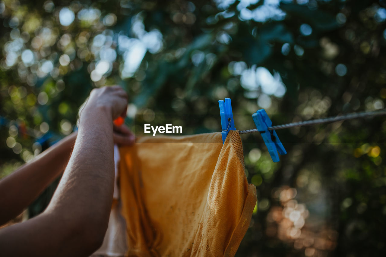 Cropped hand of woman drying clothes on clothesline