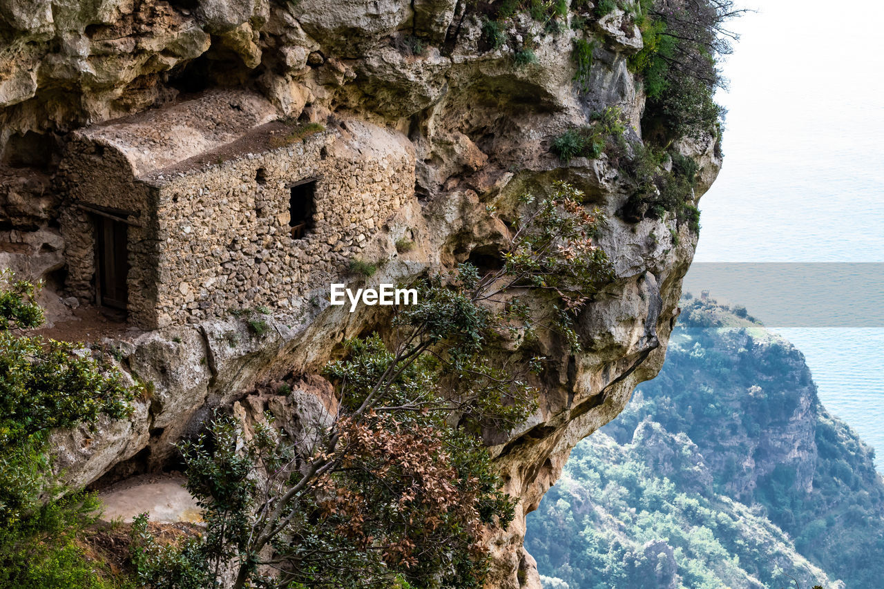 ROCK FORMATIONS BY SEA AGAINST MOUNTAIN