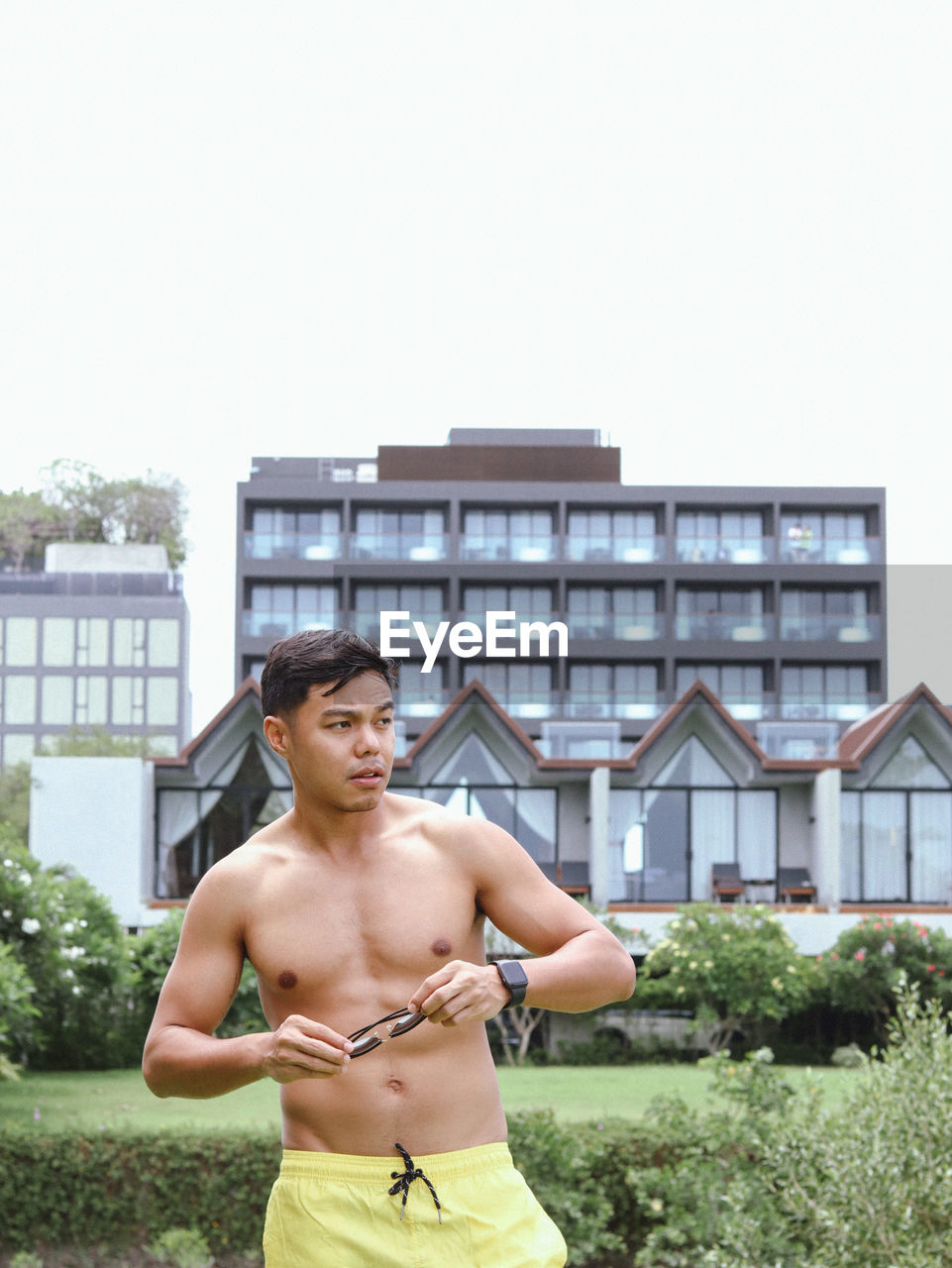Portrait of shirtless man standing against building