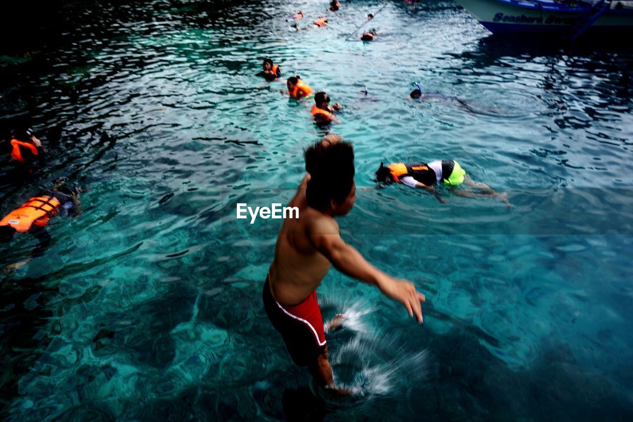 HIGH ANGLE VIEW OF PEOPLE SWIMMING IN POOL