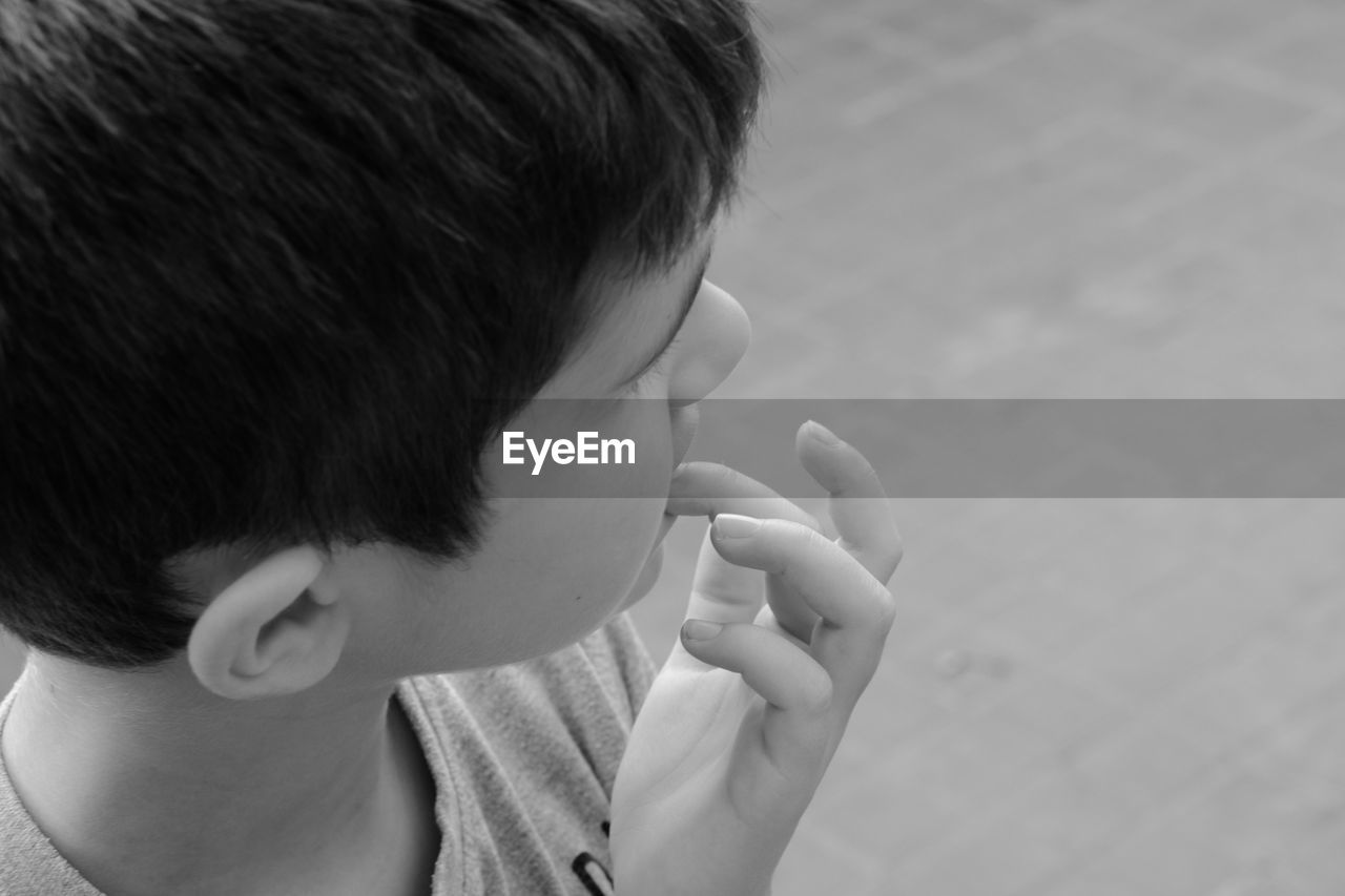 CLOSE-UP OF BOY EATING WITH HAND IN MOUTH