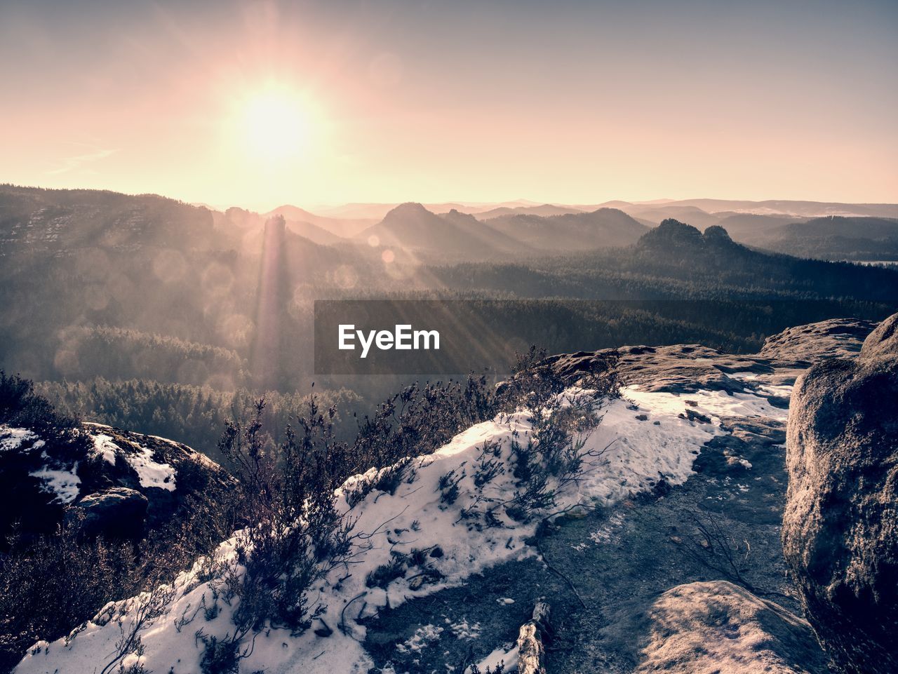 Rocky mountain peak with snow and sky with hot sun in winter, winter landscape