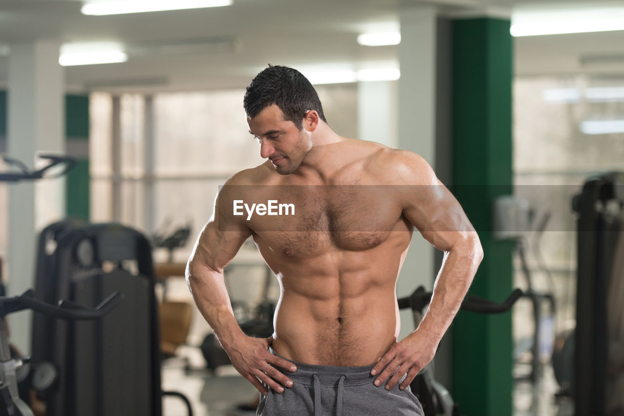 Muscular young athlete standing in gym