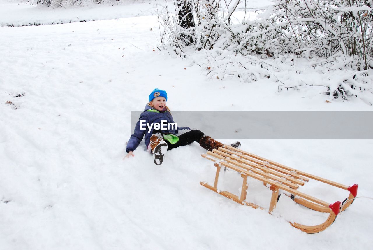 Girl falling from sled on snow during winter