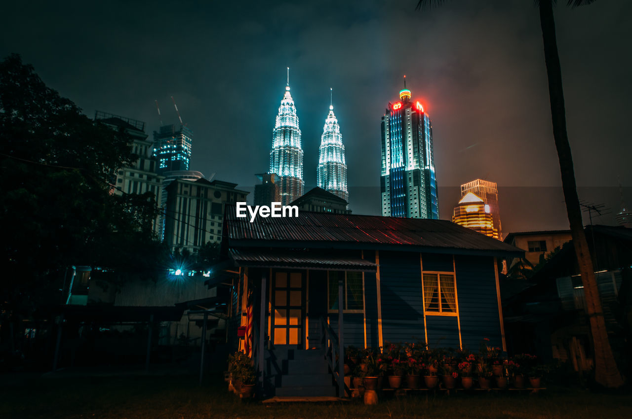 LOW ANGLE VIEW OF ILLUMINATED CITY AT NIGHT