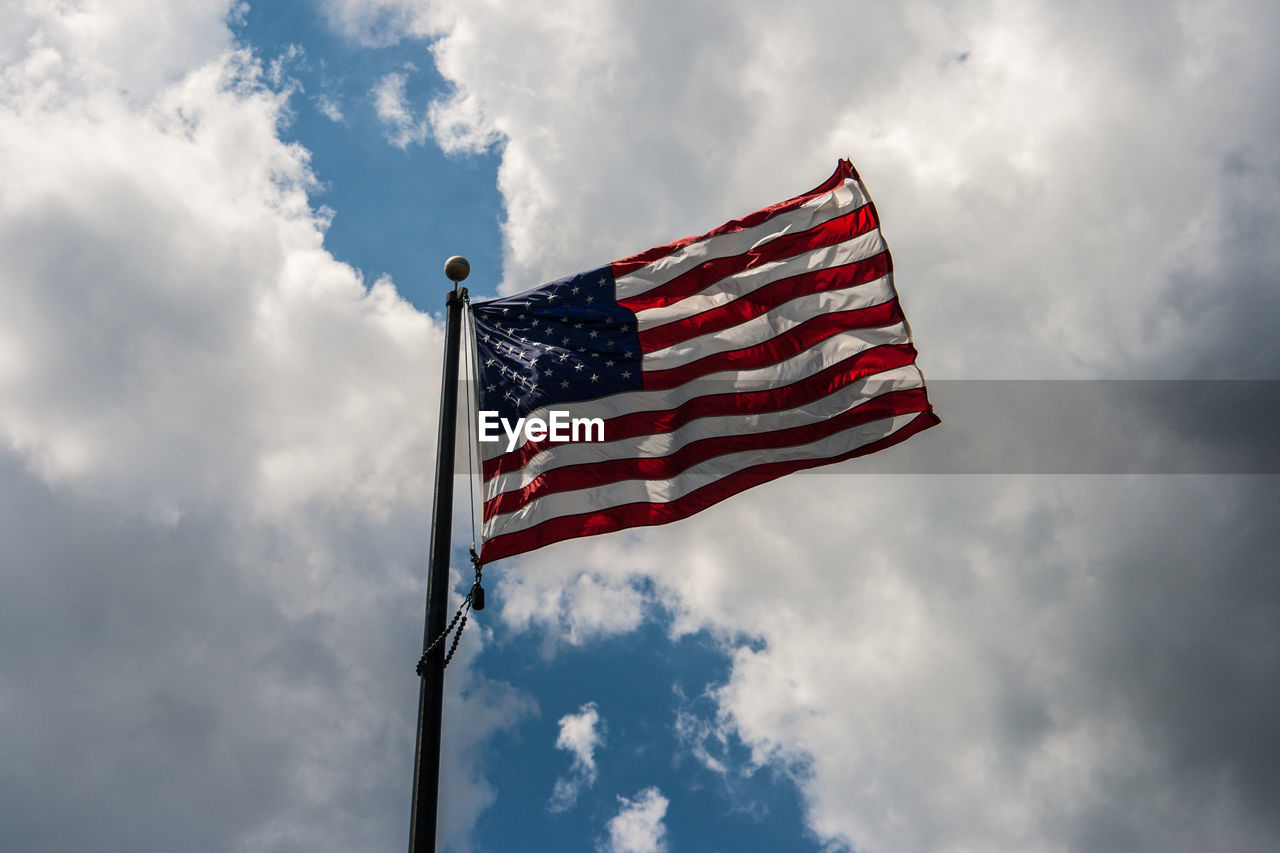 Low angle view of american flag against cloudy sky