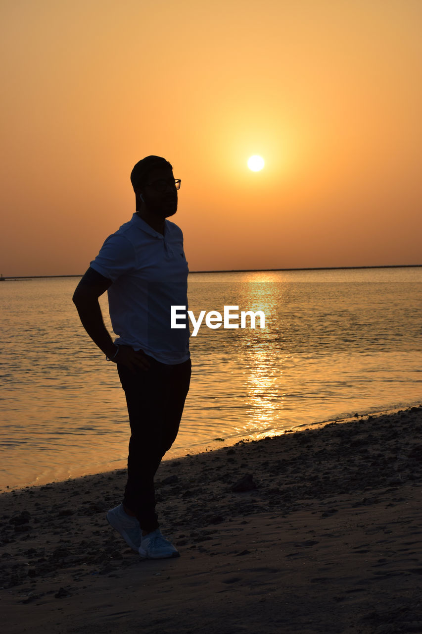 Full length of man standing on beach during sunset