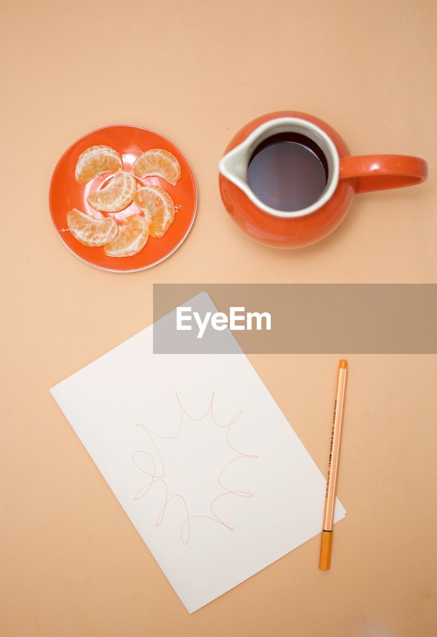 Directly above view of coffee with orange fruit and paper